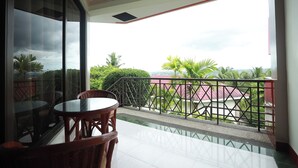 A balcony with a glass door, a round table, and wicker chairs. - Bohol Plaza Resort and Restaurant (Dauis)