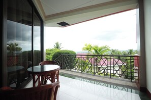 A balcony with a glass door, a round table, and wicker chairs. - Bohol Plaza Resort and Restaurant (Dauis)