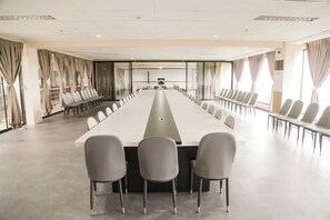 A conference room with a long table and multiple chairs, large windows with curtains, and a modern ceiling design. - Bohol Plaza Resort and Restaurant (Dauis)