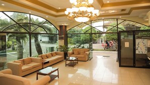 A spacious lobby with a large arched glass window, a chandelier, and a seating area with sofas and a coffee table. - Bohol Plaza Resort and Restaurant (Dauis)