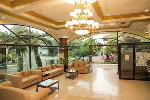 A spacious lobby with a large arched glass window, a chandelier, and a seating area with sofas and a coffee table. - Bohol Plaza Resort and Restaurant (Dauis)
