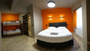 Un dormitori amb un llit superposat, un llit individual i una finestra gran amb cortines.