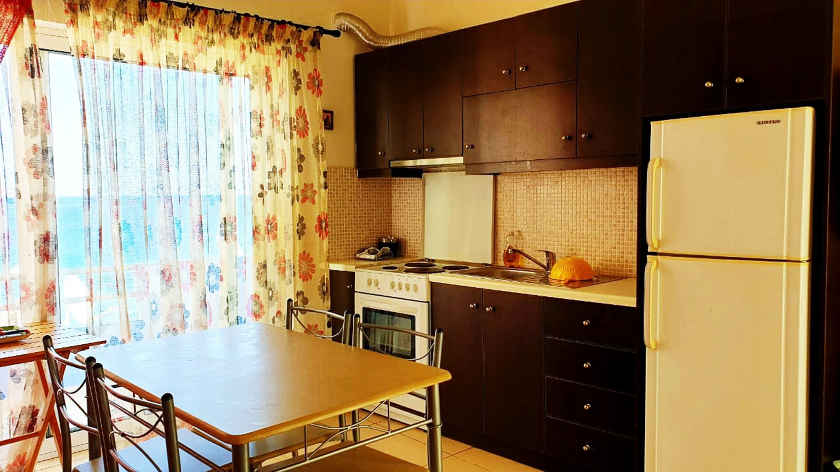 A compact kitchen with dark cabinets, a white refrigerator, a stove, and a sink.