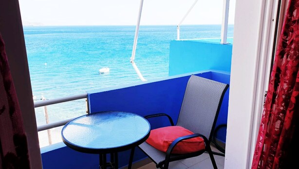 A balcony with a view of the sea, a table, and a chair with a cushion. - Homy Lovely House Near the Sea (Archanes-Asterousia)