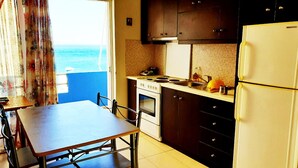 A compact kitchen with a view of the sea, a dining table, and a refrigerator. - Homy Lovely House Near the Sea (Archanes-Asterousia)