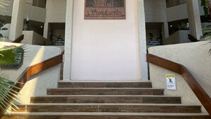 Une entrée d’immeuble avec une enseigne indiquant « Châteaux de sable » et un escalier menant à l’étage.