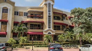Hotel com vários andares, varandas, toldos vermelhos e uma torre vertical central.