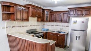 Uma cozinha com armários de madeira, fogão, pia e geladeira.