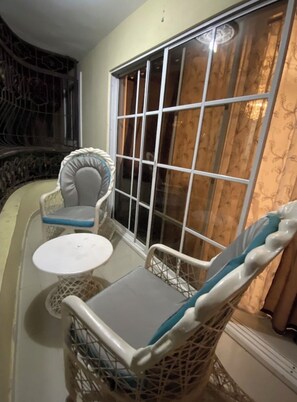 A corner room with a large window, a small round table, and two wicker chairs with cushions. - 🌆5Amazing huge! Nice furnished apt 2  long term stay (Santo Domingo)