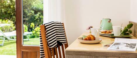 A breakfast table with a croissant, a green kettle, and a cup.
