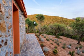 Un edificio de piedra con una puerta roja y un camino de piedra que lleva a una colina con árboles.