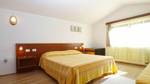 A hotel room with a large bed, a bedside table, a nightstand, a window with curtains, and a wall-mounted light fixture. - Apartment 2003/28453 (Istria - Premantura), 500m from the beach (Premantura)