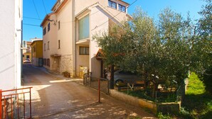 A narrow street with a building featuring a balcony and a tree in the foreground. - Apartment 2003/28453 (Istria - Premantura), 500m from the beach (Premantura)