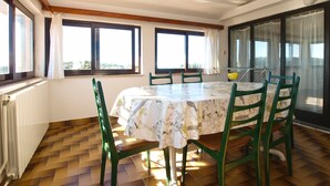 A dining area with a table and chairs, large windows, and a view of the outdoors. - Apartment 2003/28453 (Istria - Premantura), 500m from the beach (Premantura)