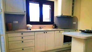 A kitchen with white cabinets, a window above the sink, and a tiled floor.