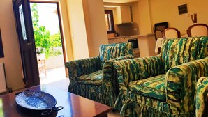 A living room with two patterned sofas, a wooden coffee table, and a door leading outside.