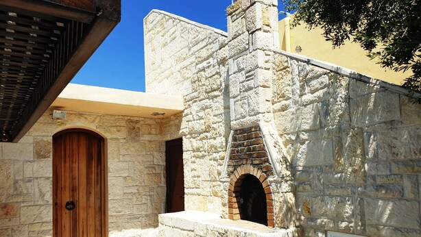 A stone building with a wooden door and arched windows.
