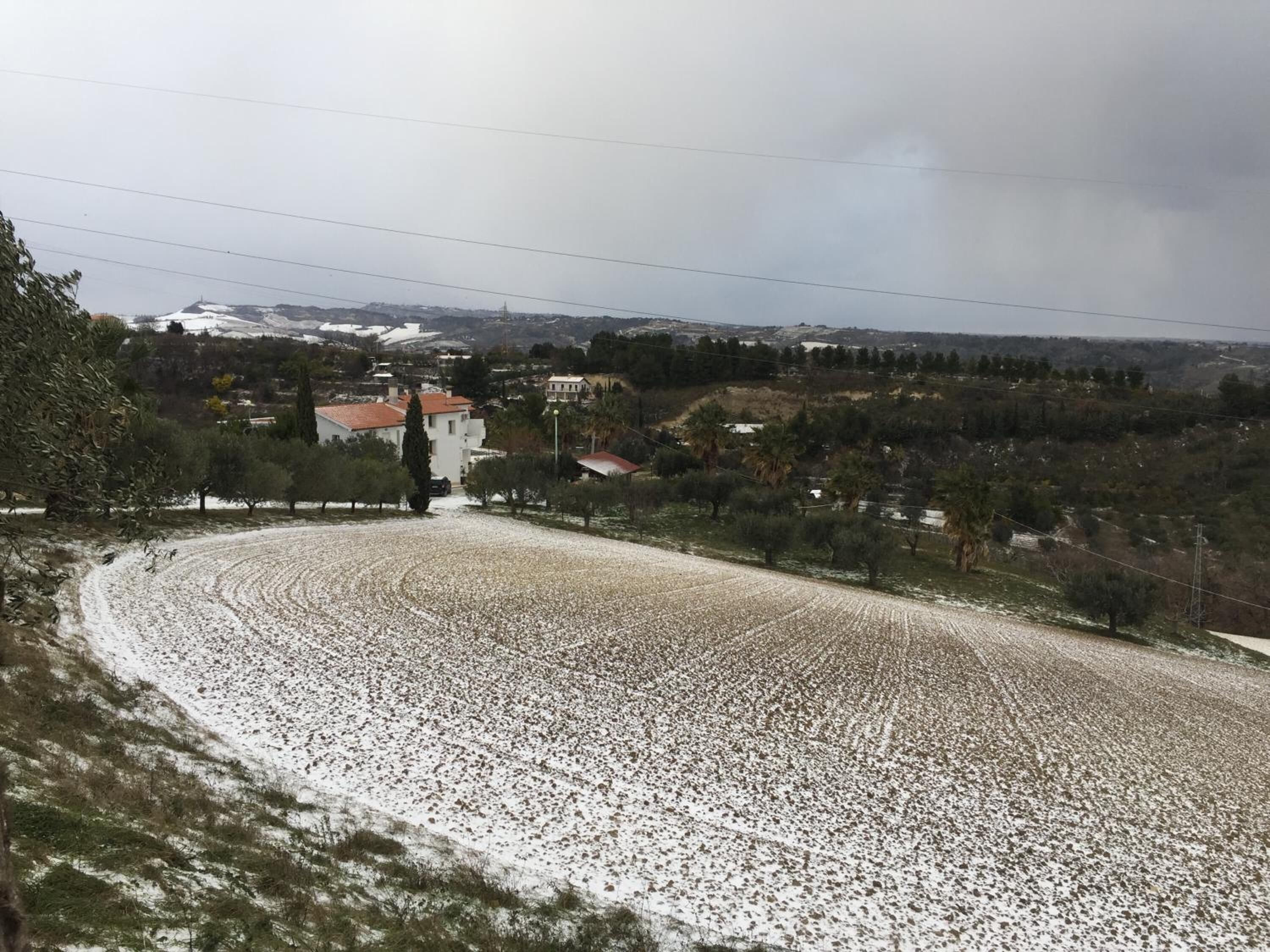 A rural landscape with a winding road, a church, and scattered buildings.