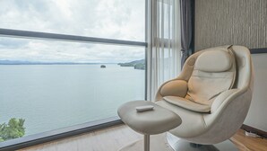 A modern room with a large window offering a view of a calm body of water and distant land. - Hotel Urban Island (Namhae)