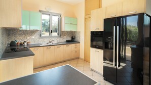 Uma cozinha moderna com armários de madeira, uma geladeira preta e uma janela que oferece luz natural.