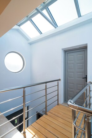 Un escalier en bois avec des rampes en métal menant à une porte surmontée d’une fenêtre.