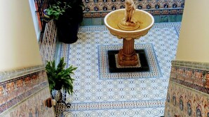 A staircase with ornate blue and white patterned tiles, a central fountain, and potted plants. - Casa Museo La Merced (Málaga)