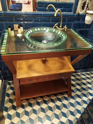 A bathroom with a glass sink, wooden vanity, and blue and white patterned tiles. - Casa Museo La Merced (Málaga)