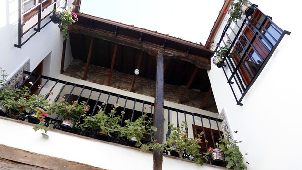 A balcony with wooden beams, potted plants, and a metal railing. - Casa Museo La Merced (Málaga)