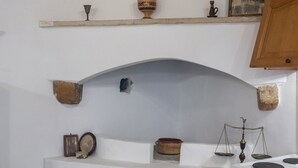 Eine Küche mit weißer Arbeitsplatte, einem Herd und Regalen mit verschiedenen Küchenutensilien.