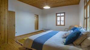 Ein Schlafzimmer mit Holzboden, einem Bett mit blau-weißer Bettwäsche, einem Fenster und einer Heizung.