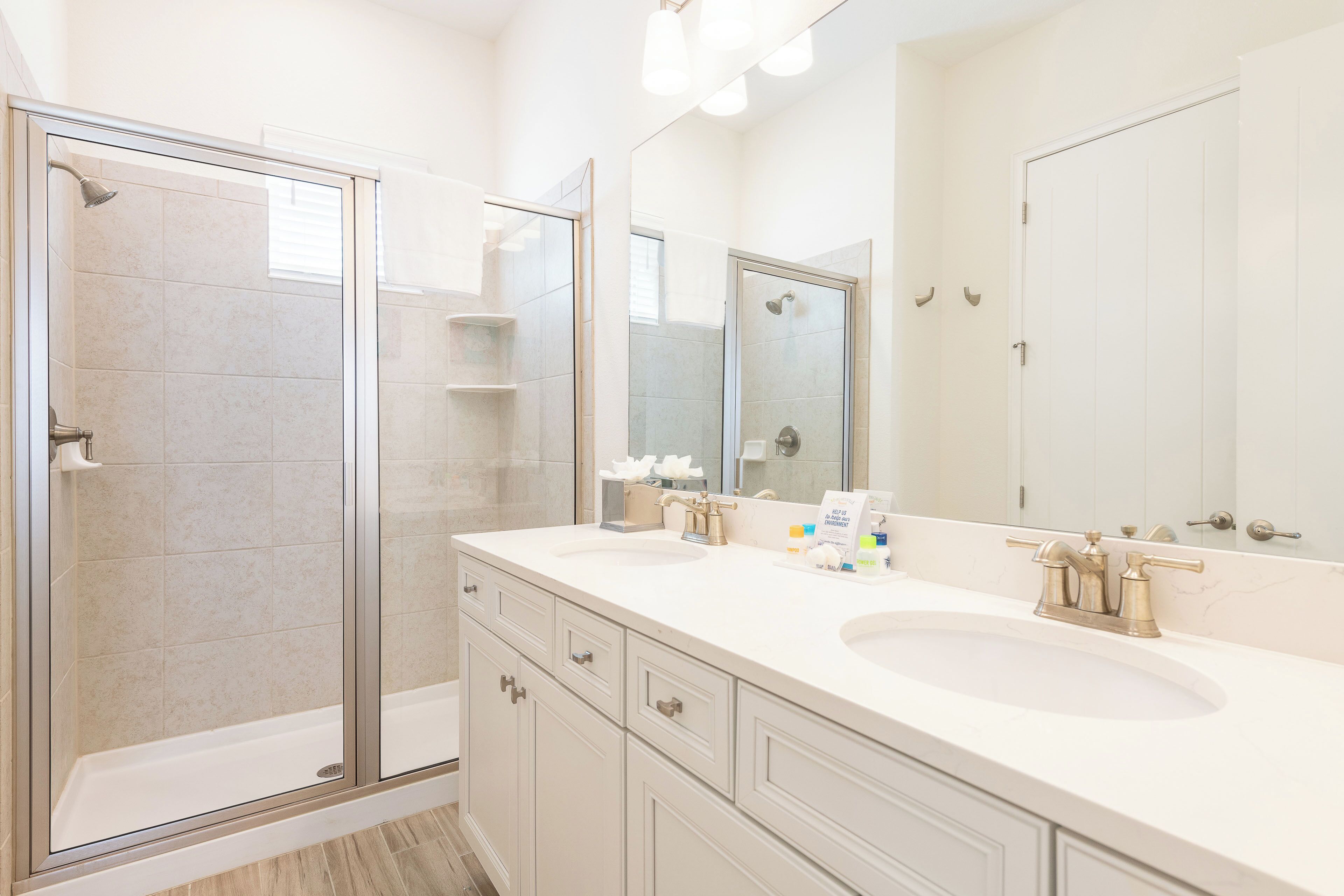 A modern bathroom with a glass-enclosed shower, a double sink vanity, and a large mirror.
