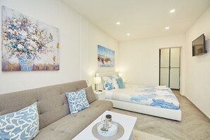 Un dormitorio moderno con sofá, cama y obras de arte en las paredes.