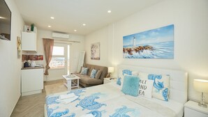 Habitación de hotel con cama, escritorio, sofá y un cuadro de un faro.