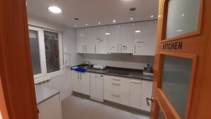 Uma cozinha compacta com armários brancos, pia e bancada.