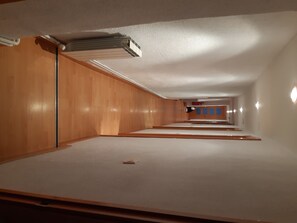 Un long couloir étroit d’hôtel, avec des lambris en bois sur les murs et un appareil de climatisation fixé au plafond.
