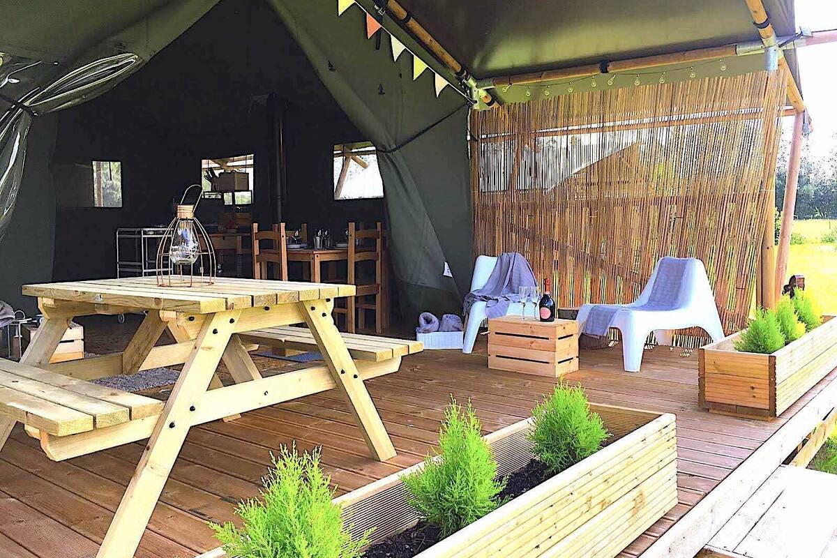 Une terrasse en bois avec une table de pique-nique, des chaises et des jardinières remplies de plantes vertes.