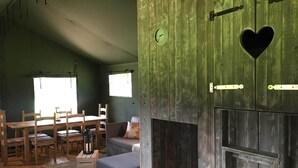A rustic interior with a wooden dining table, chairs, a sofa, and a fireplace with a heart-shaped cutout. - Wingfield Escapes (Diss)