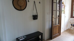 A room with a wooden door, a black bench, a hat on the wall, and a black bag hanging on hooks. - La Turr de Mezz- Bellagio Lca (Bellagio)