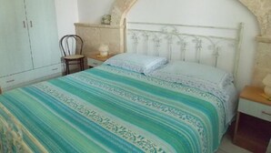 Quarto com cama, guarda-roupa, cadeira e mesa de cabeceira.