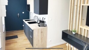 Cozinha moderna com porta azul escura, armários de madeira e bancada preta.