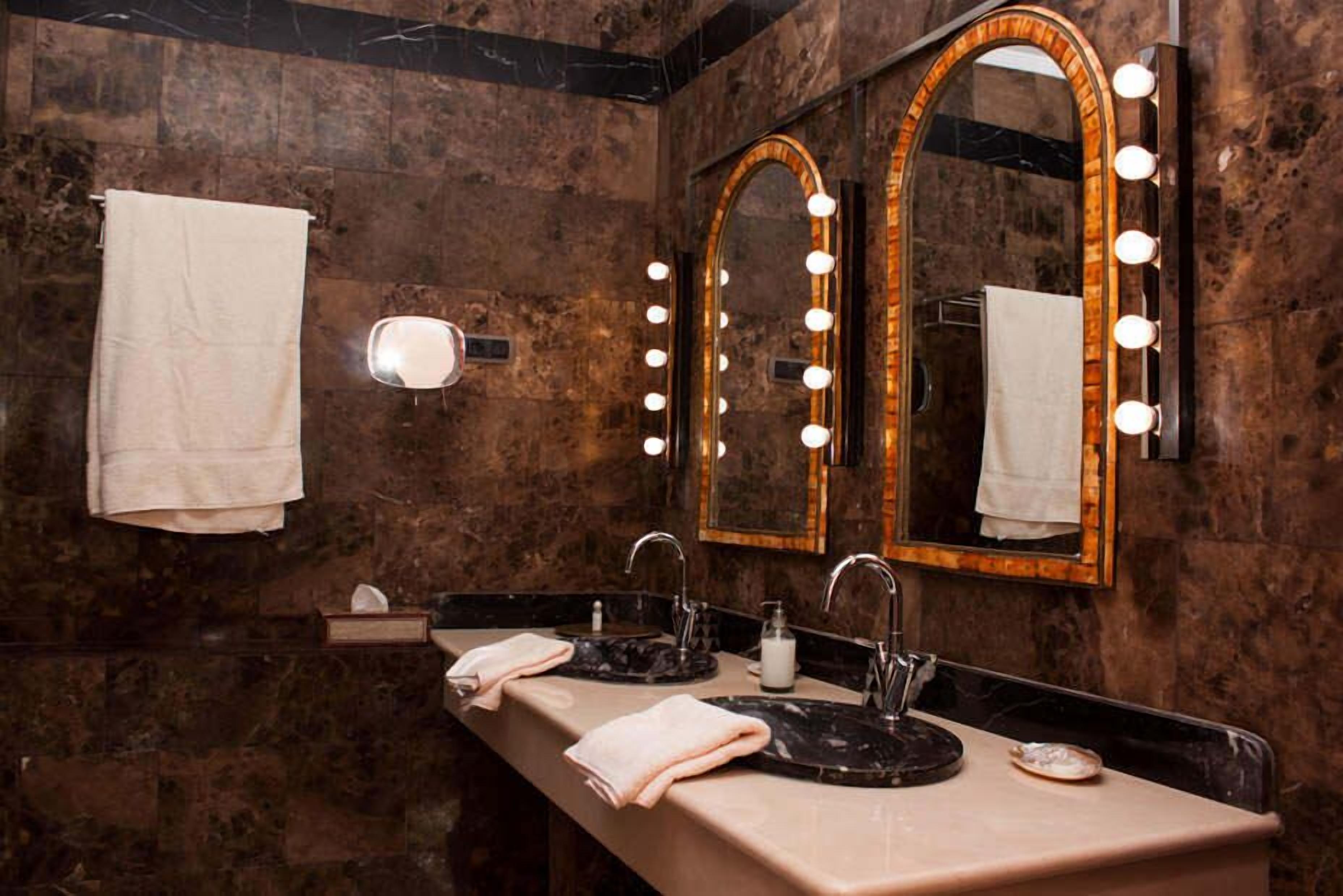Une salle de bain avec deux lavabos, un miroir de coiffeuse avec éclairage et un porte-serviettes.