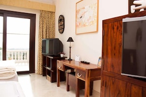 Une chambre d’hôtel avec un bureau en bois, une télévision, une lampe et une grande armoire.