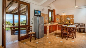 Eine Küche mit einer großen Kochinsel, Holzstühlen, einem Kühlschrank und einem Fernseher.