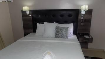 A hotel room with a large bed, two bedside lamps, a nightstand, and a neatly made bed with a towel.