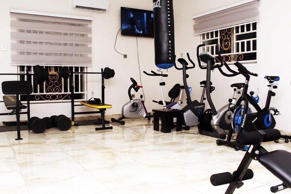 A gym with various exercise equipment, including treadmills, stationary bikes, and weight machines. - C'ron Hotels and Suites (Port Harcourt)