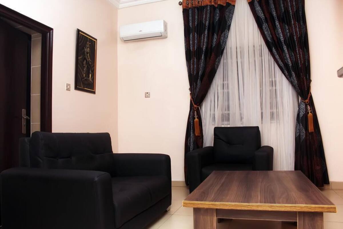 A living room with two black sofas, a wooden coffee table, and a black armchair.