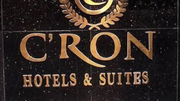 En receptionsdisk med en vägg som har en gyllene, strukturerad yta, två klockor och en logotyp med en lagerkrans.