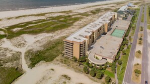 Luchtbeeld van een kusthotel met meerdere gebouwen, een strand en een weg.