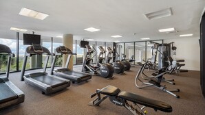 Een fitnessruimte met loopbanden, elliptische trainers en gewichten.