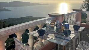 Un balcó amb taula a punt per dinar, amb vista a una massa d'aigua i terres llunyanes.